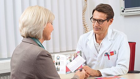 Arzt berät Patientin Arzt berät Patientin anhand einer Broschüre - Arzt berät Patientin